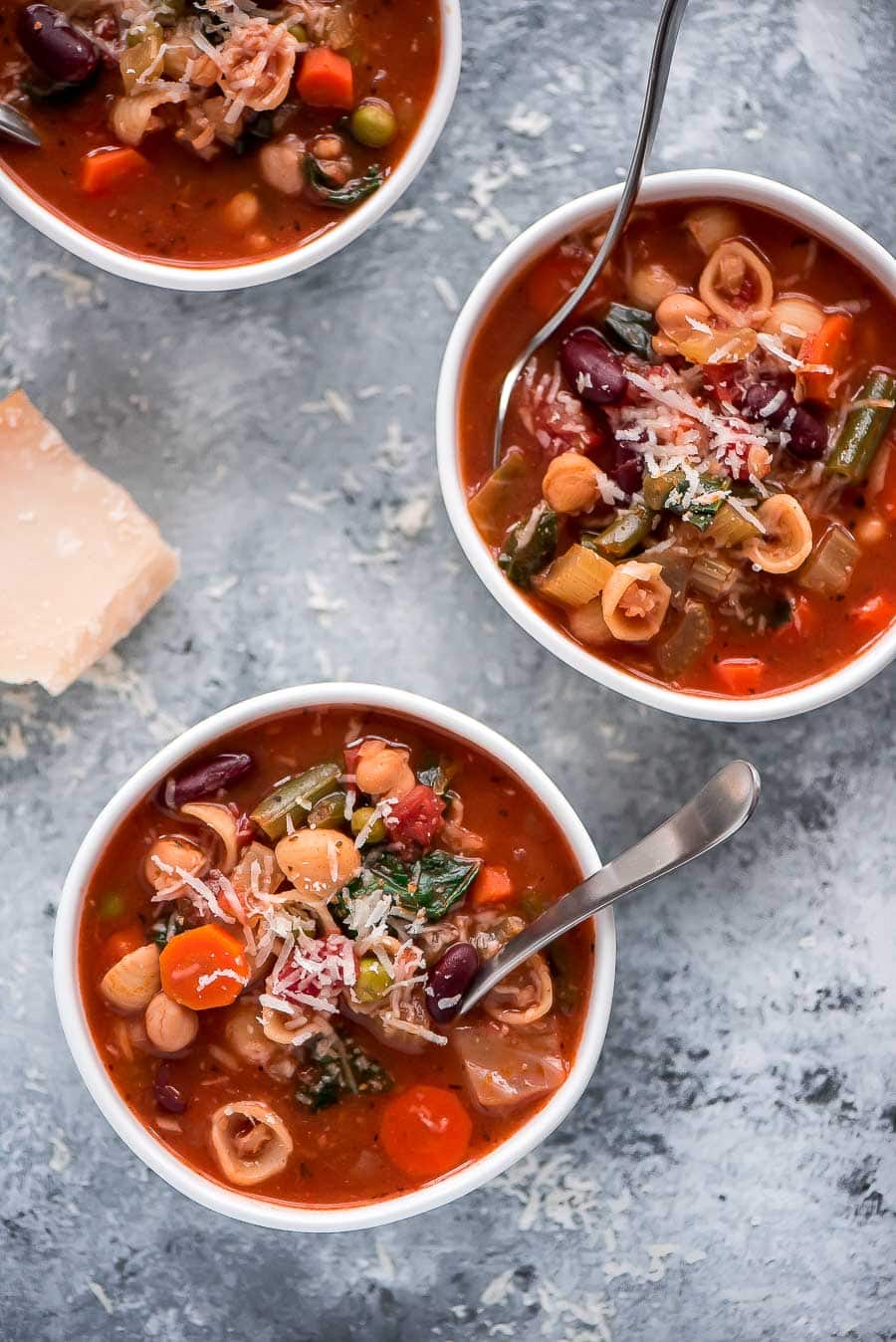 3 bowls of Minestrone soup topped with grated cheese.