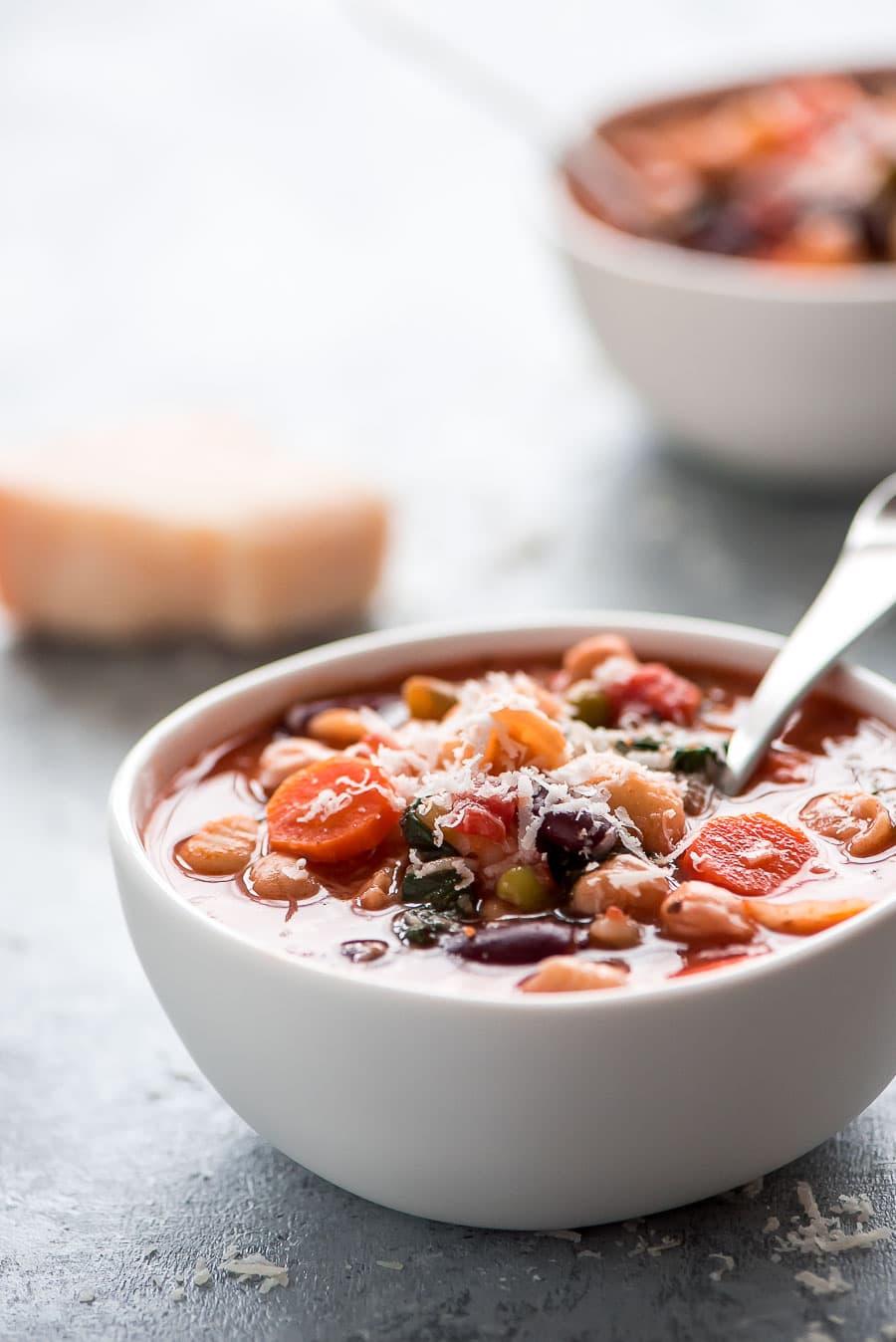 Minestrone Soup served in a white bowl and garnished with cheese.