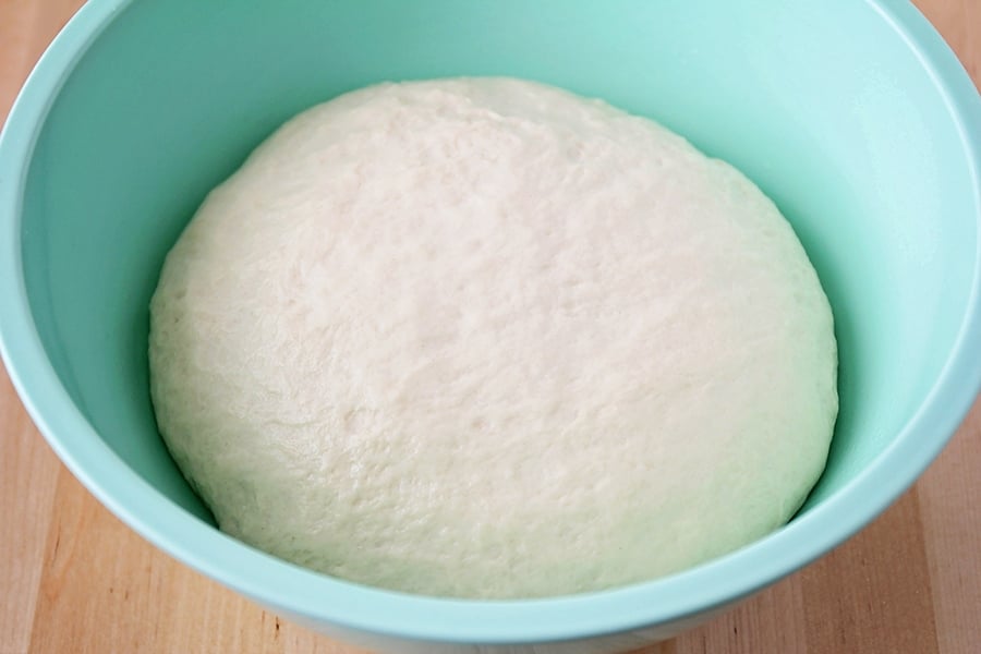 Breadstick dough rising in a turquoise bowl.