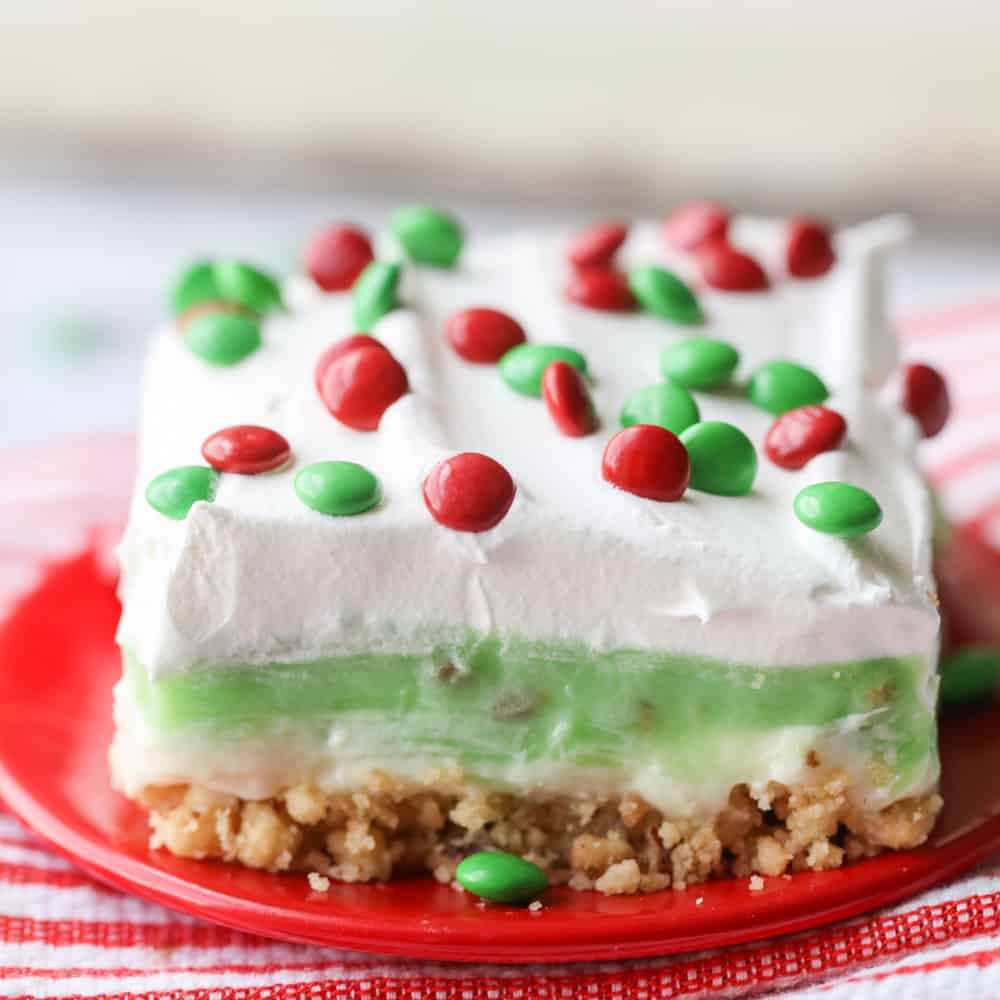 Candy topped slice of pistachio dessert on a plate.