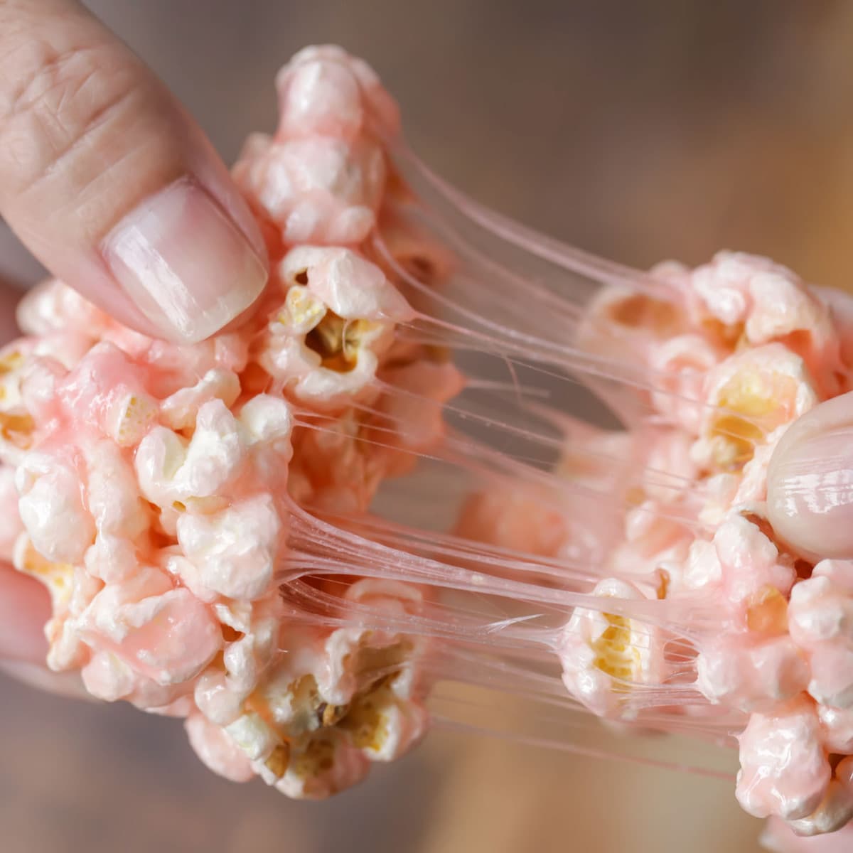 Marshmallow popcorn ball being pulled in half .