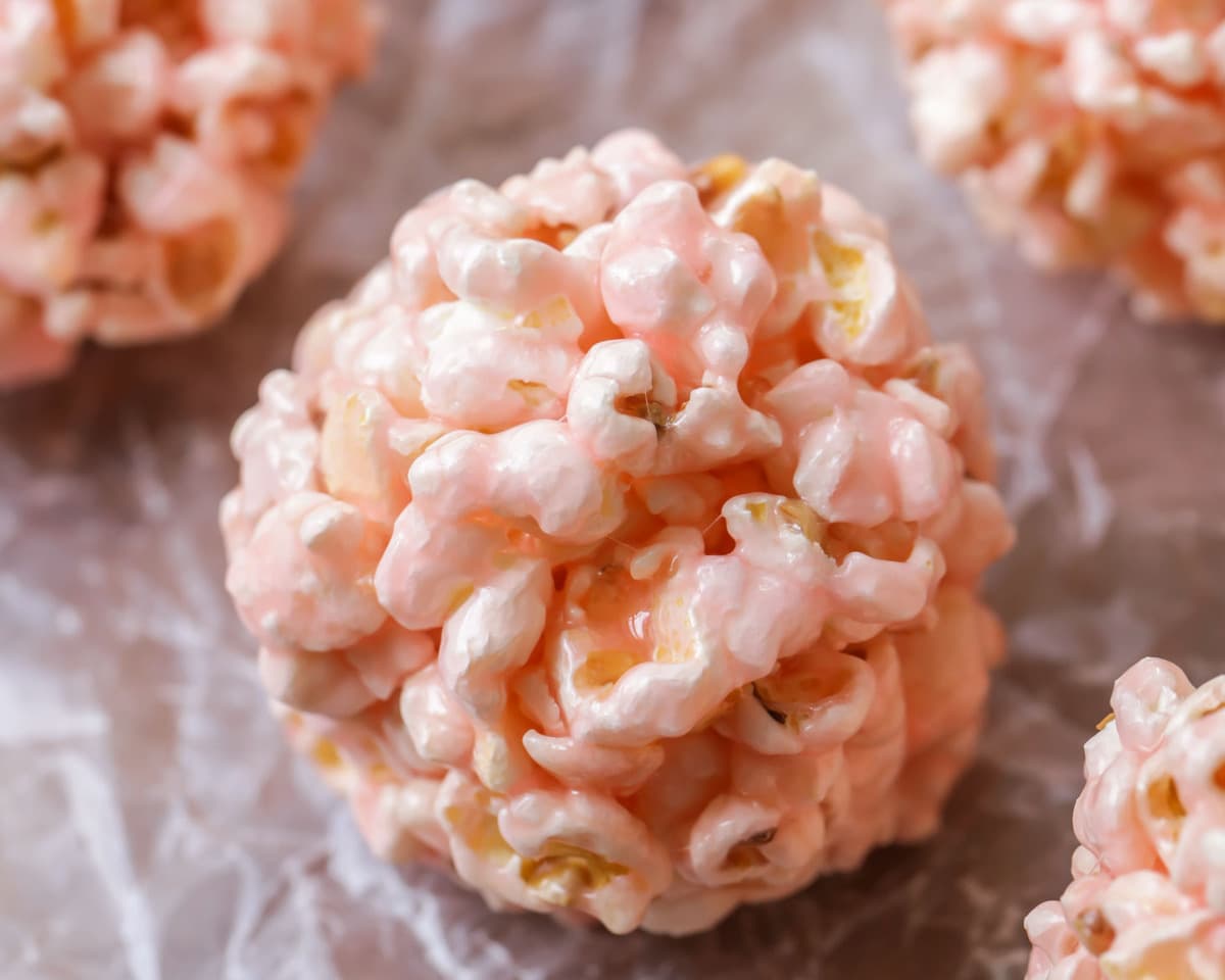 Pink easy Popcorn Balls sitting on parchment paper.