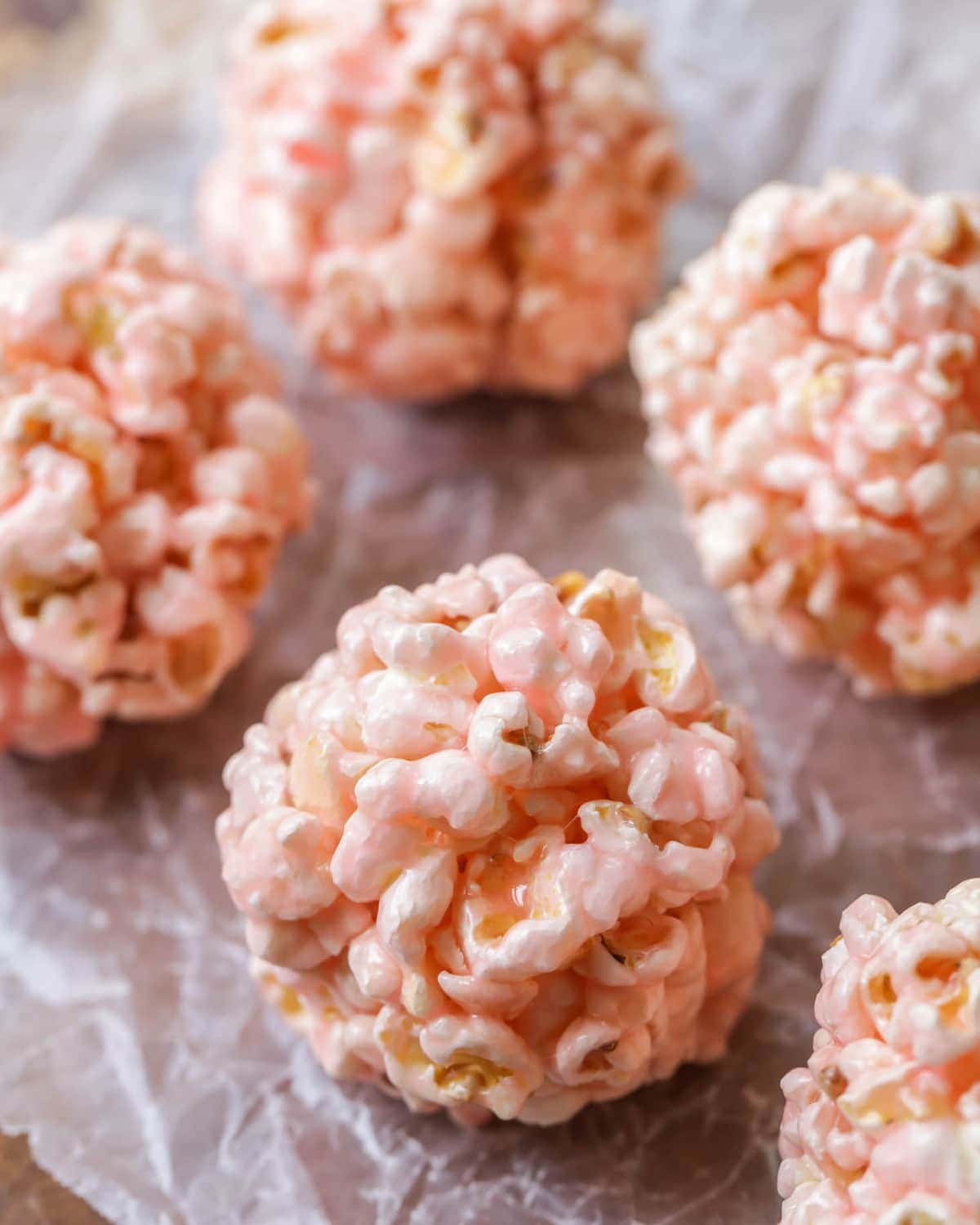 Pink Popcorn Balls sitting on parchment paper. 