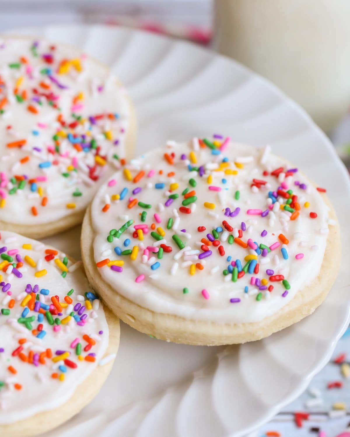Frosted sugar cookies on white cake stand.