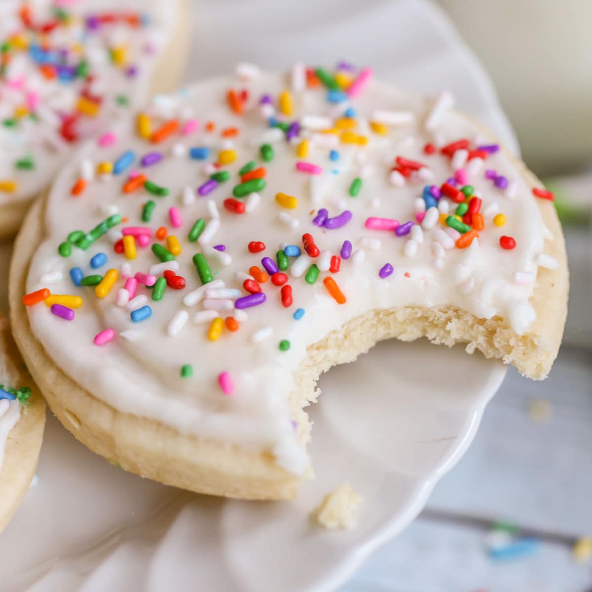 Bite taken out of Frosted Sugar cookie on cake stand.