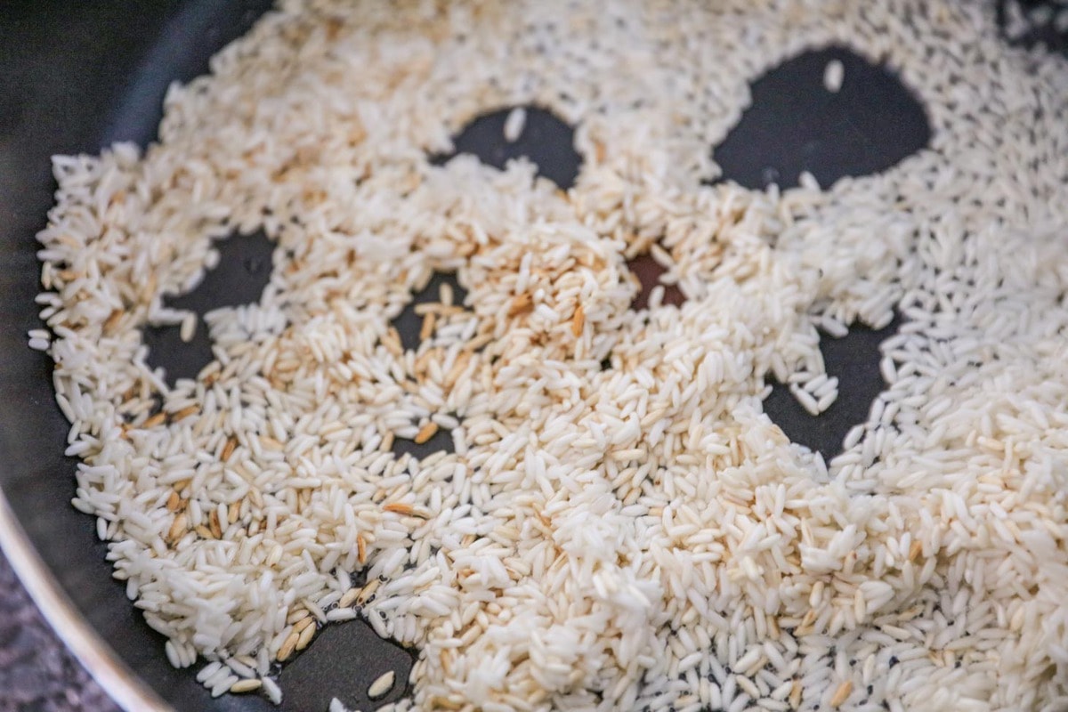 Making Mexican Rice - rice, broth, tomato sauce and seasonings in a skillet