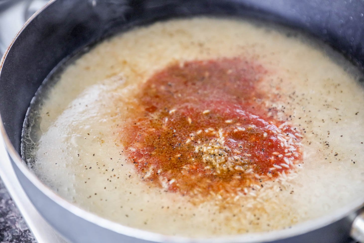 Making Mexican Rice - rice, broth, tomato sauce and seasonings in a skillet