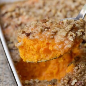 Scooping sweet potato casserole from a baking dish.