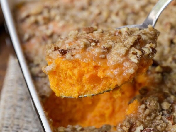 Scooping sweet potato casserole from a baking dish.