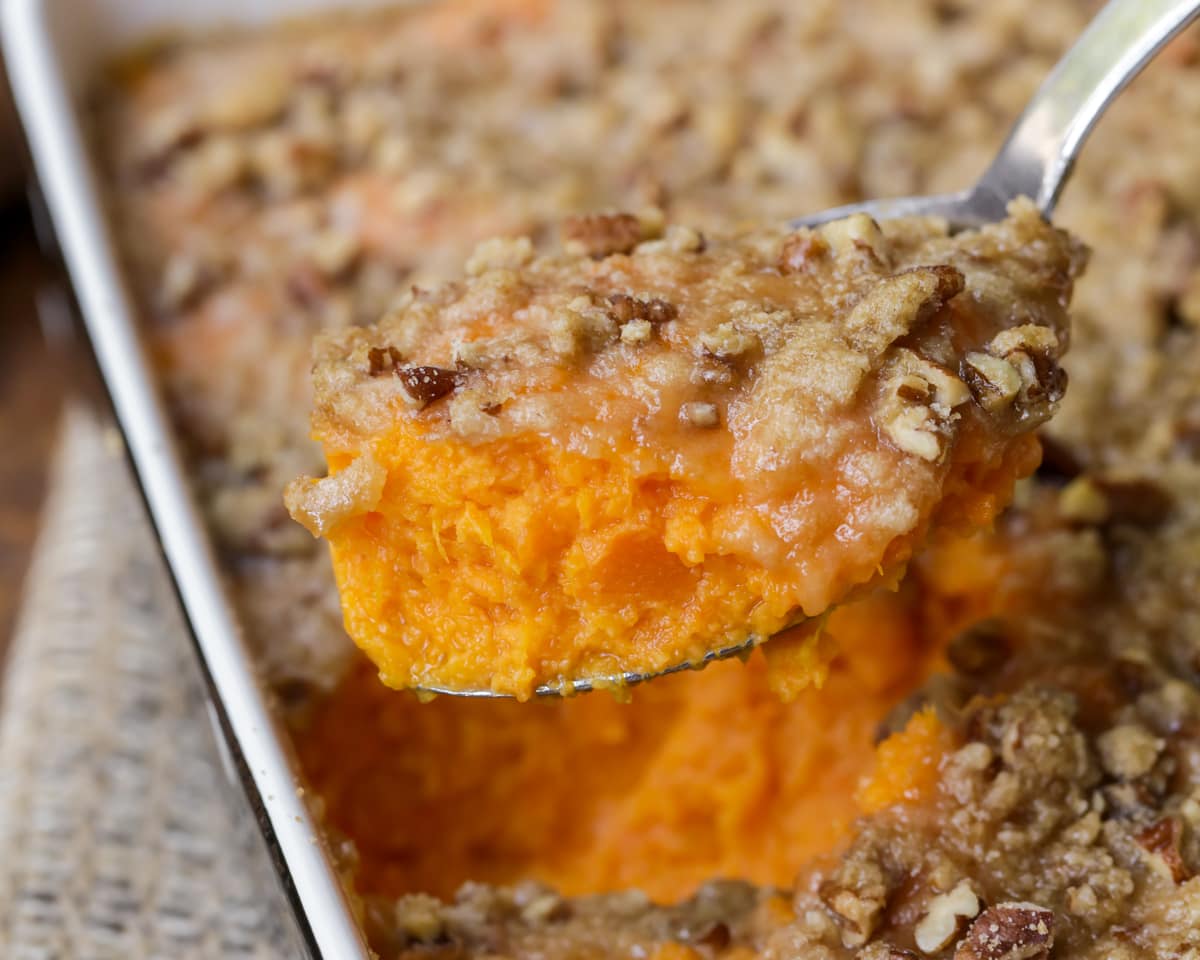 Classic sweet potato casserole spooned out of a baking dish.