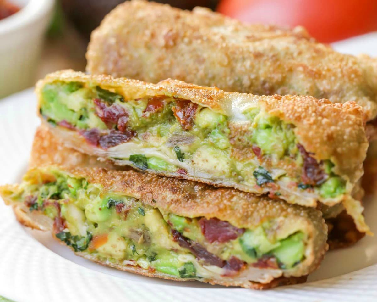 Sliced cheesecake factory Avocado Egg Rolls on a white plate.