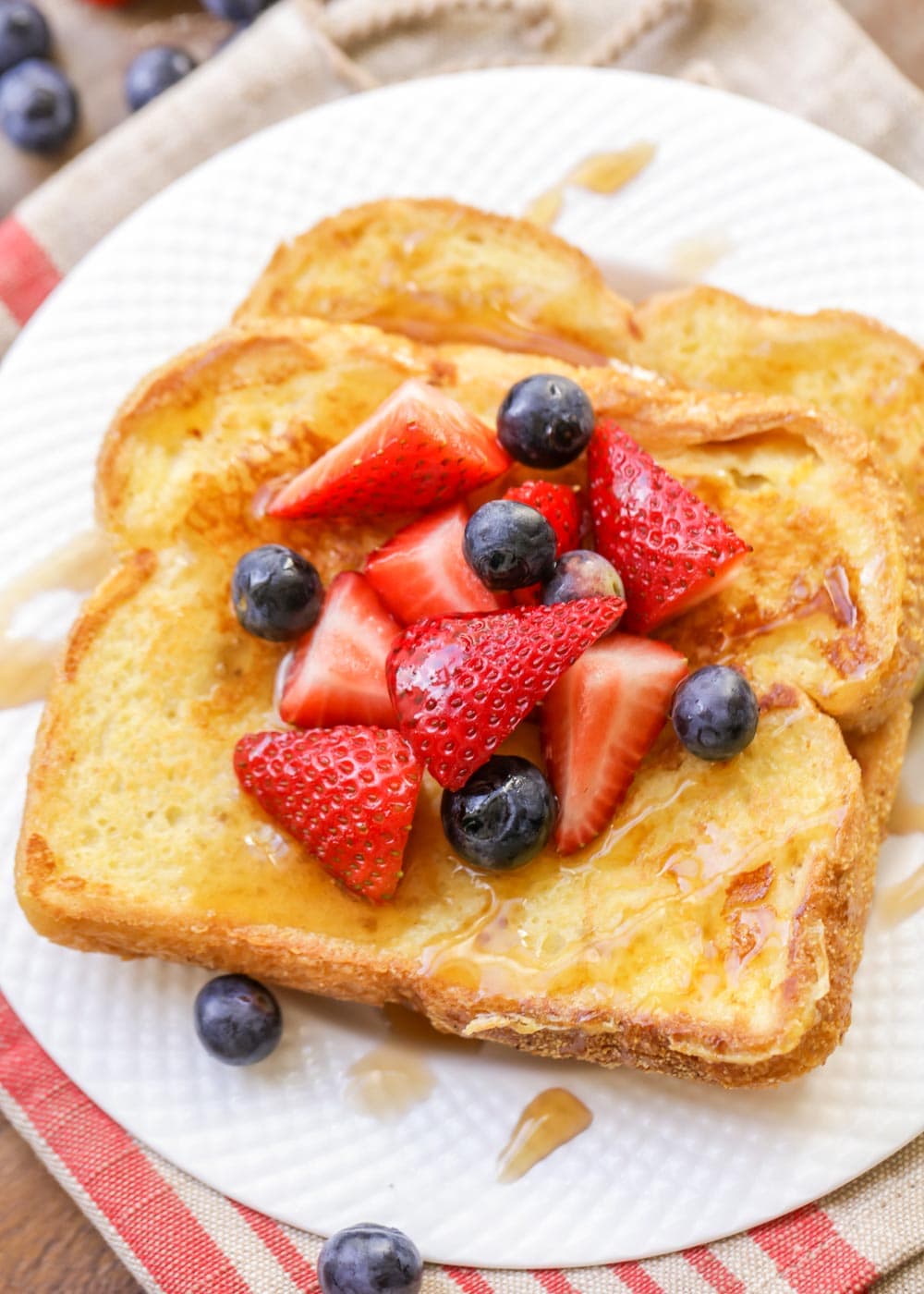 Eggnog french toast topped with berries on a white plate