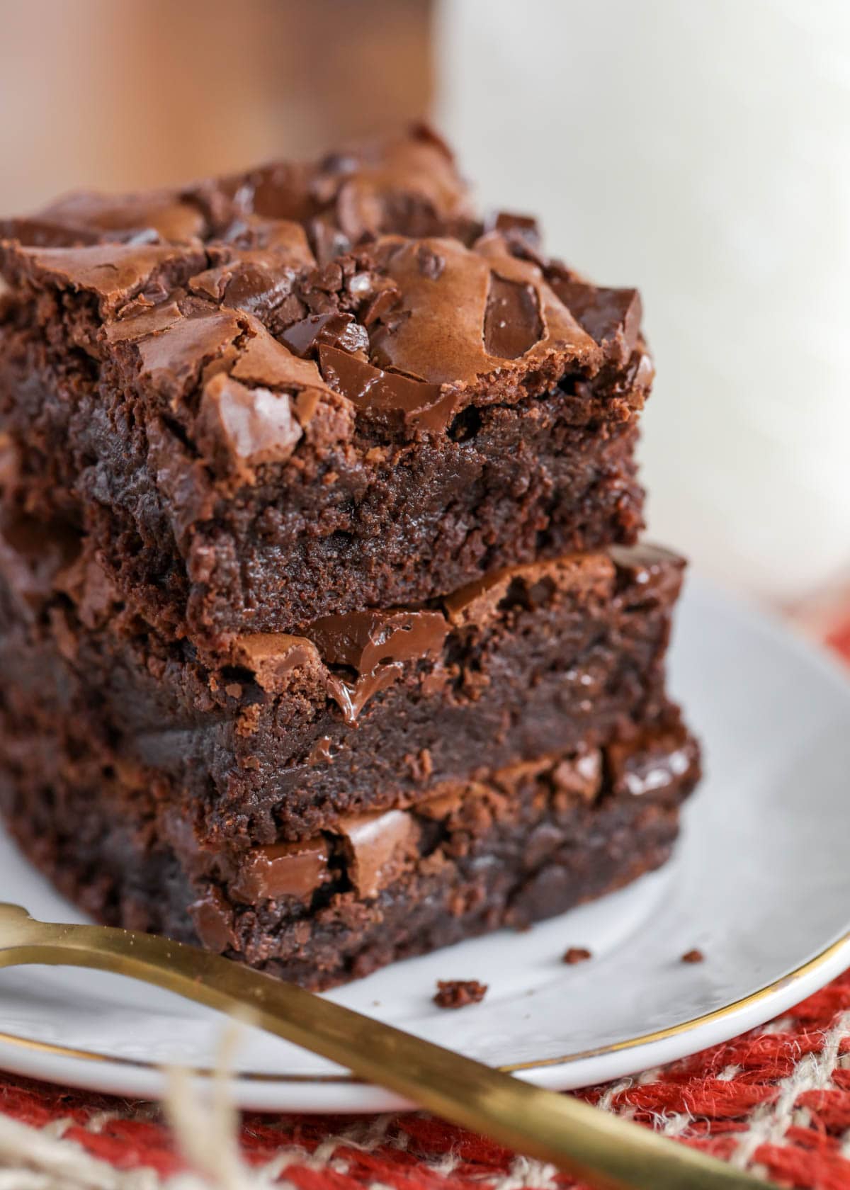 3 fudgy brownies stacked on a white plate.