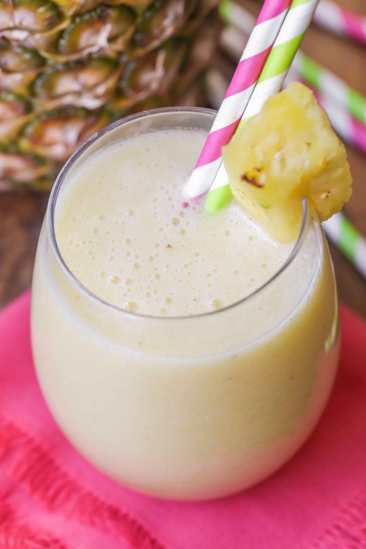 A Frothy glass of pineapple banana smoothie with a pineapple garnish.