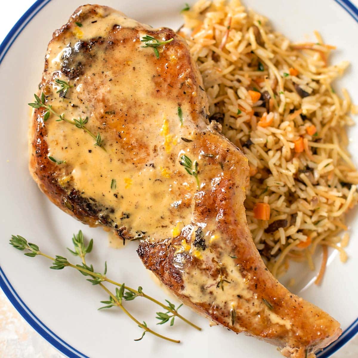 Smothered pork chop served on a plate with rice