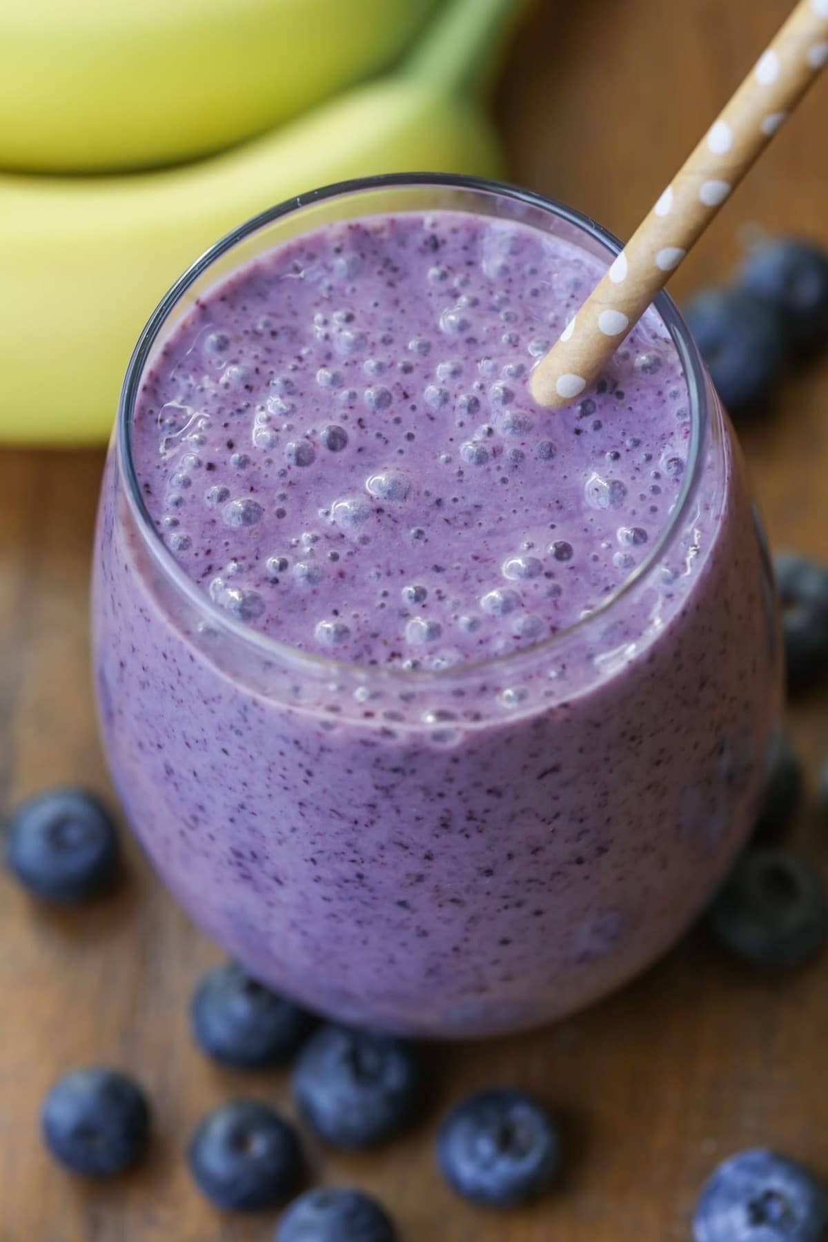 Blueberry smoothie served in a glass with a straw.