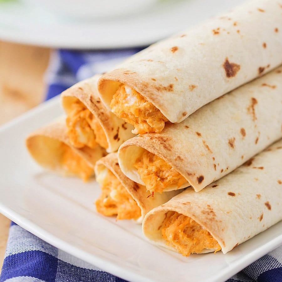 New Year's Eve Appetizers - buffalo chicken taquitos piled on a white plate.