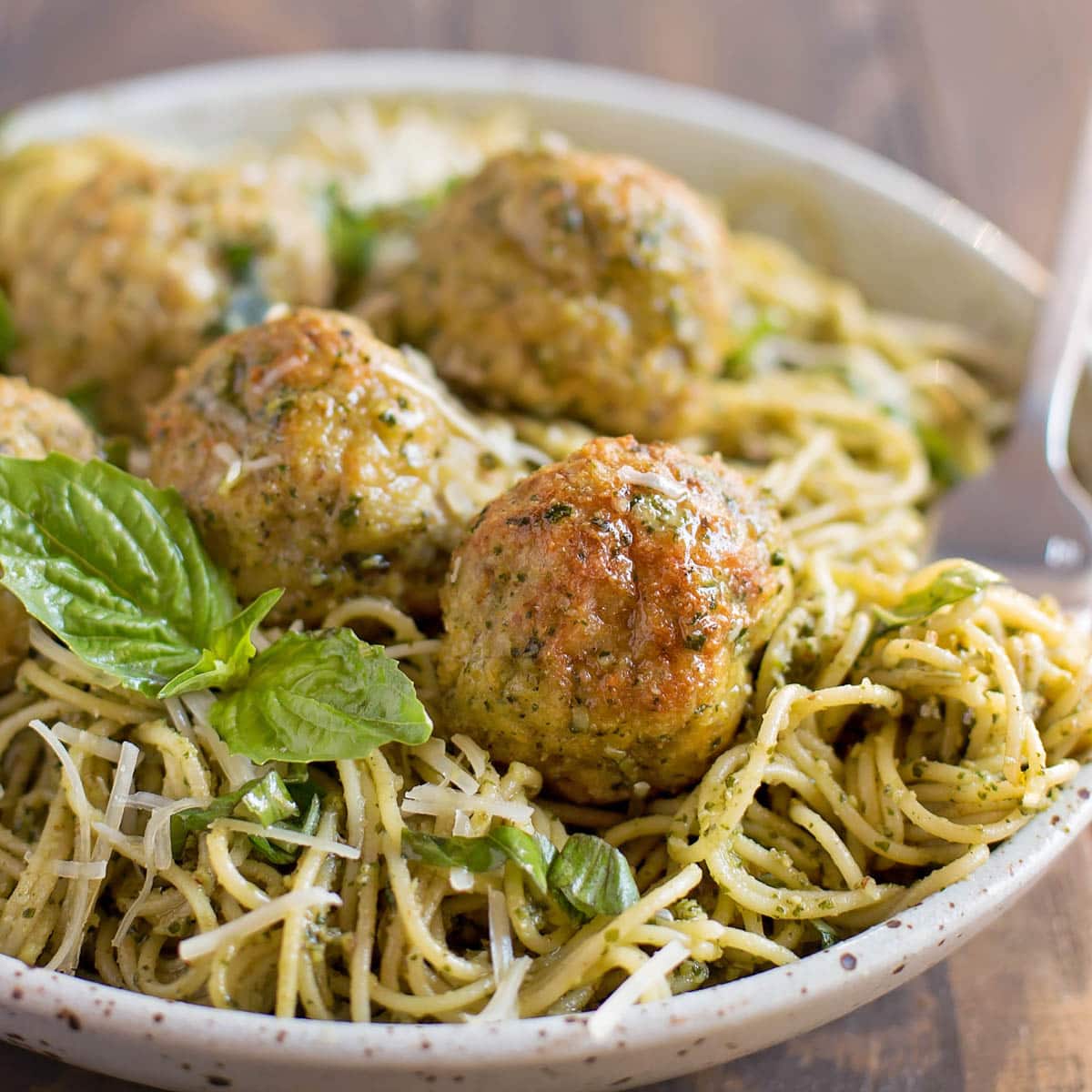 Chicken pesto meatballs served with a bowl of pesto pasta