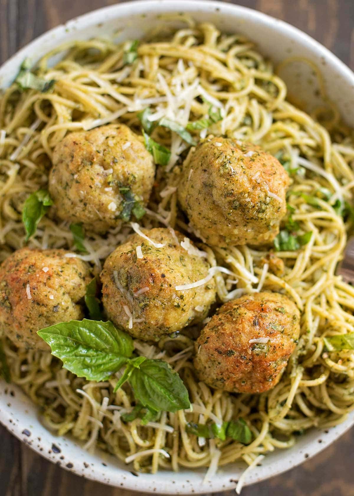 Pesto chicken meatballs on top of pesto pasta in a bowl