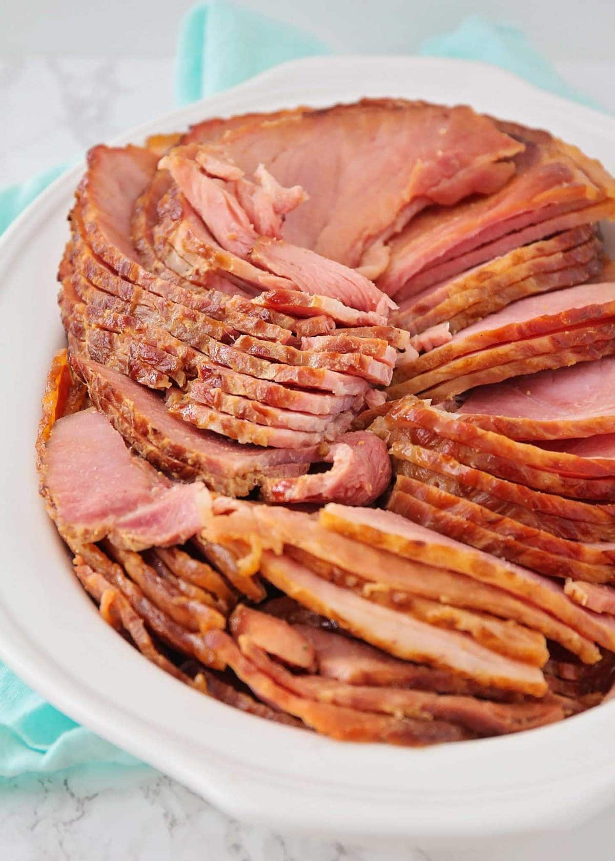 Easy honey glazed ham sliced in a serving dish.