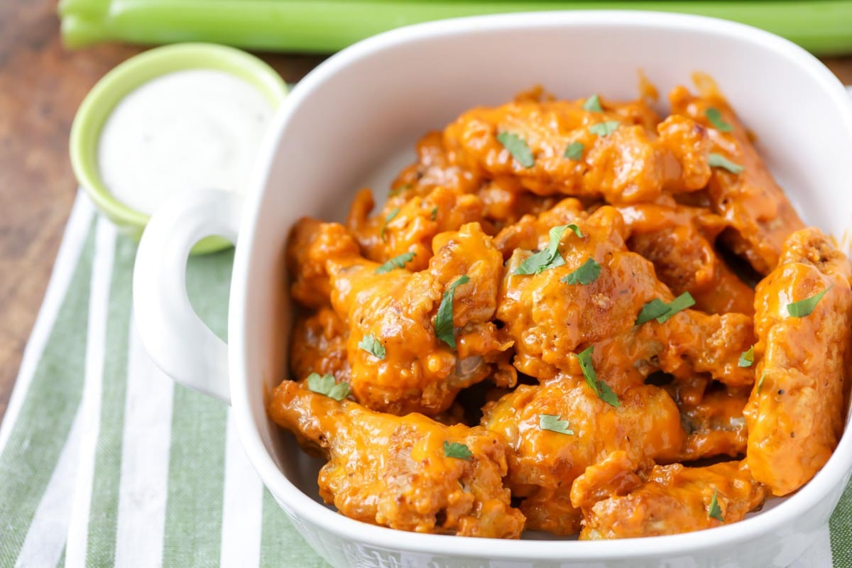 Baked buffalo wings in a large white bowl.