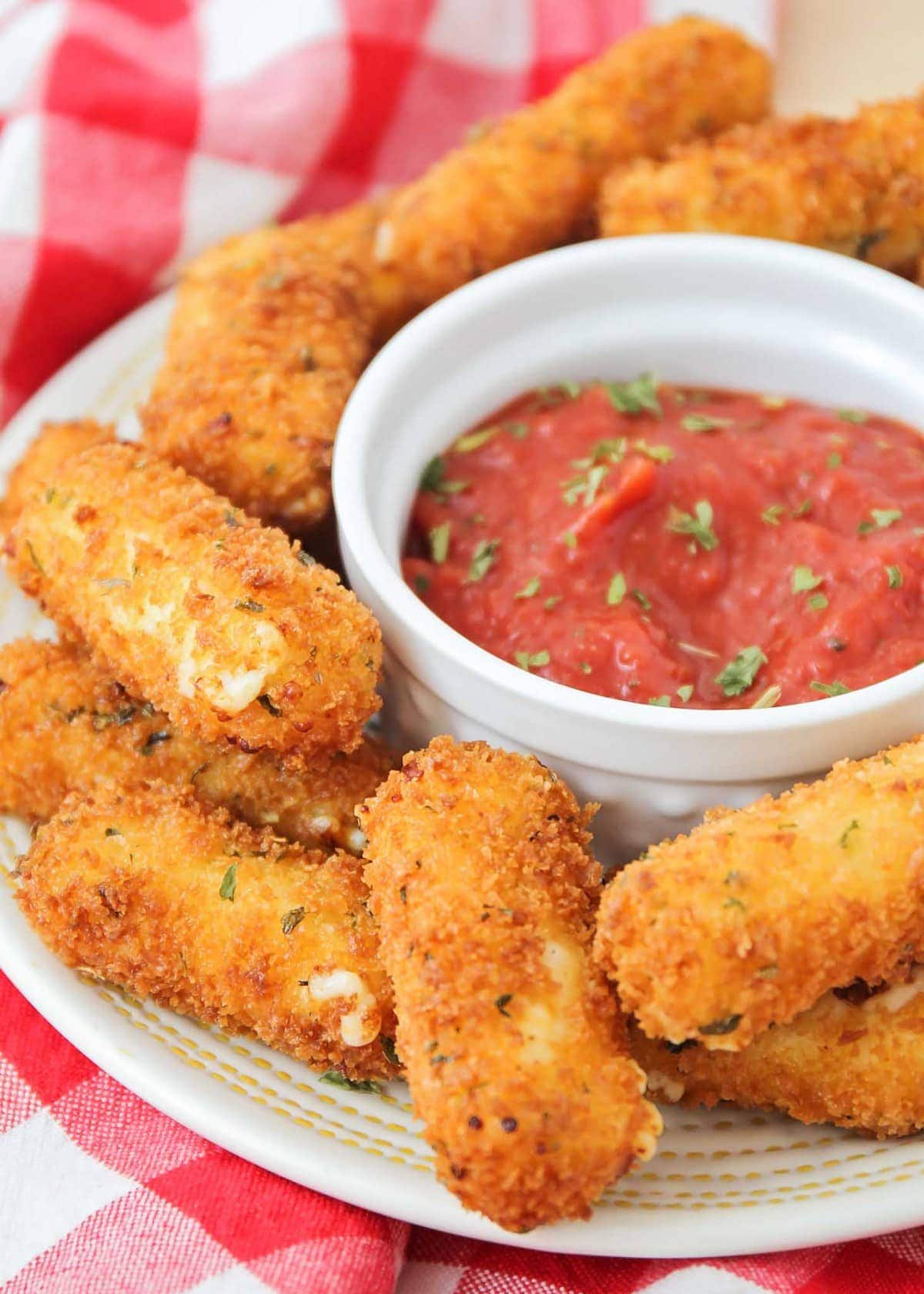 Easy mozzarella sticks on a serving platter with dipping sauce.