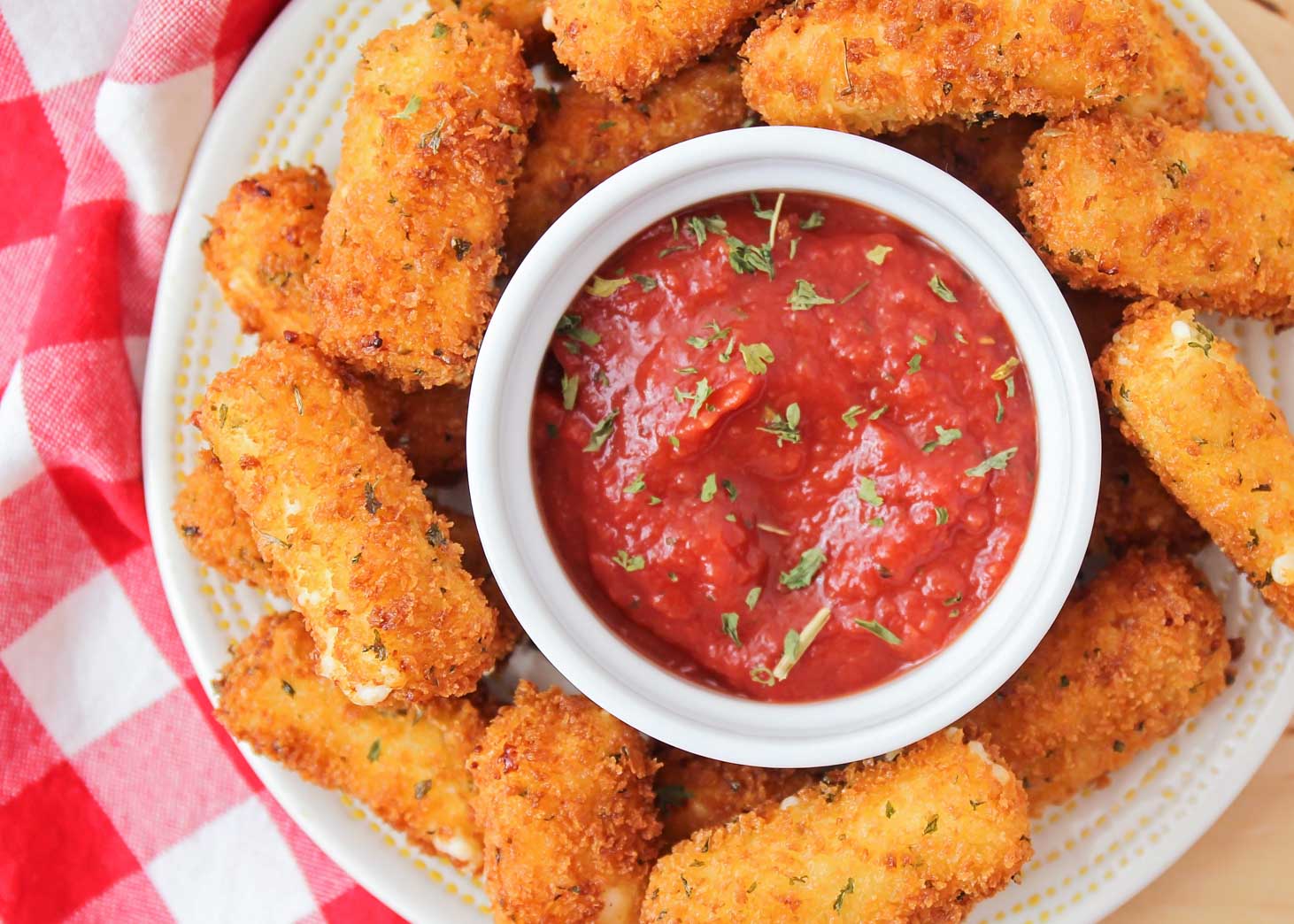 Mozzarella sticks on a platter with marinara dipping sauce.