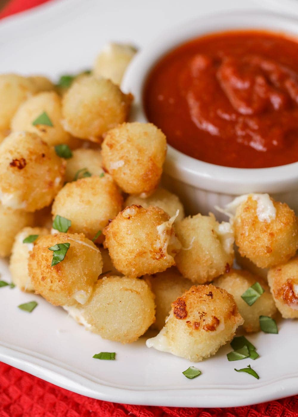 Mozzarella bites on a white platter with a side of marinara.