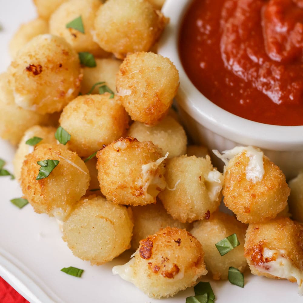 Super Bowl Appetizers - Mozzarella bites with a side of marinara sauce on a white plate. 