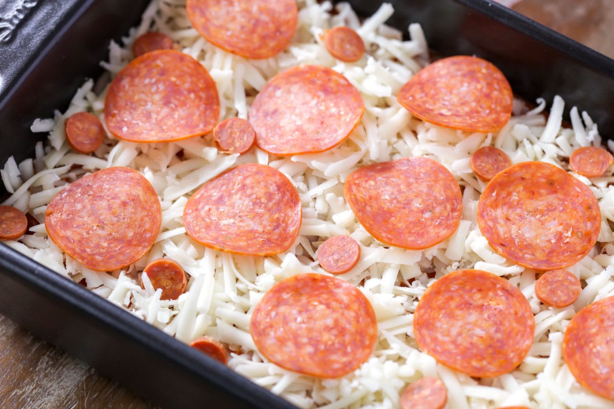 Adding toppings for pepperoni pizza dip