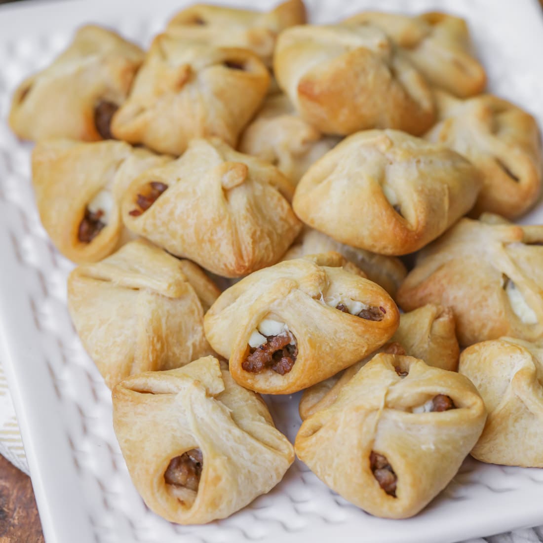 Sausage cream cheese crescent rolls piled onto a white plate