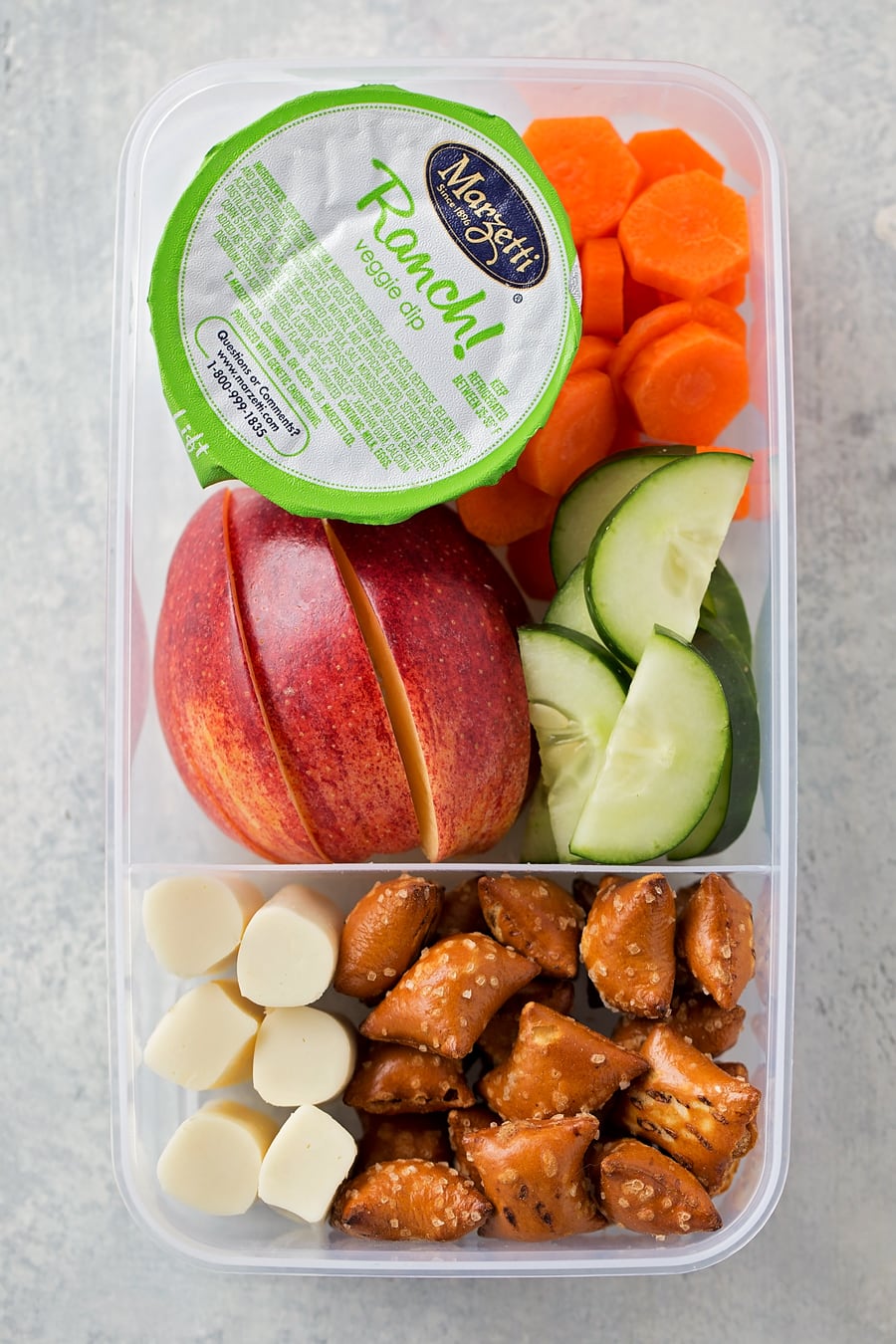 Lunch box idea with pretzels, cheese, apples, cucumber, and carrots