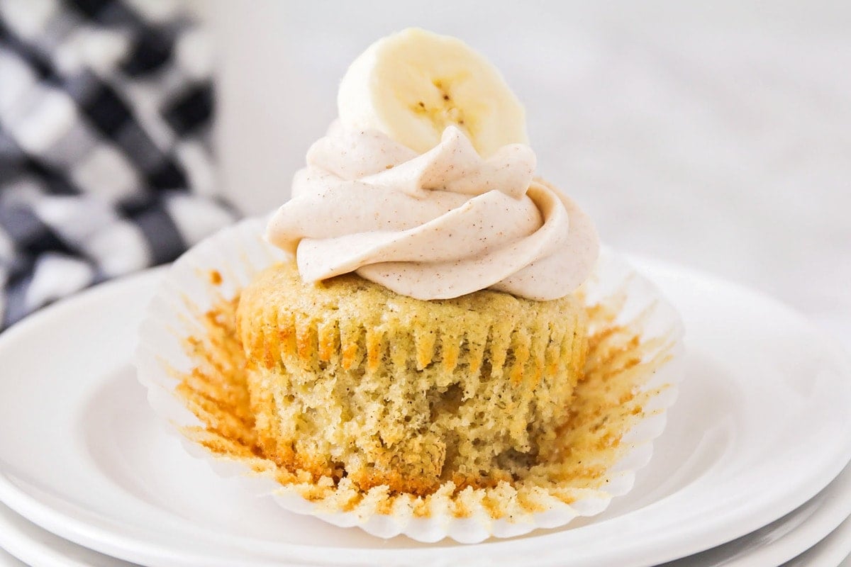 Banana cupcake with cinnamon cream cheese frosting served on a plate.
