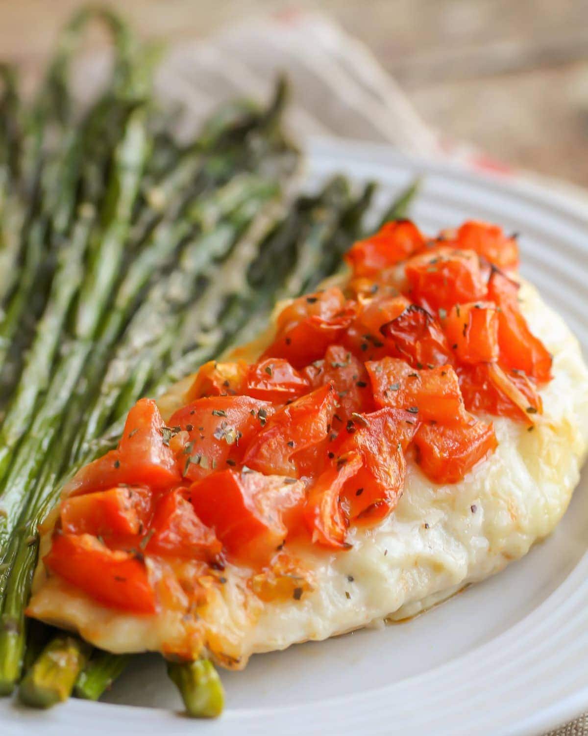 Bruschetta Chicken recipe served with asparagus on a white plate