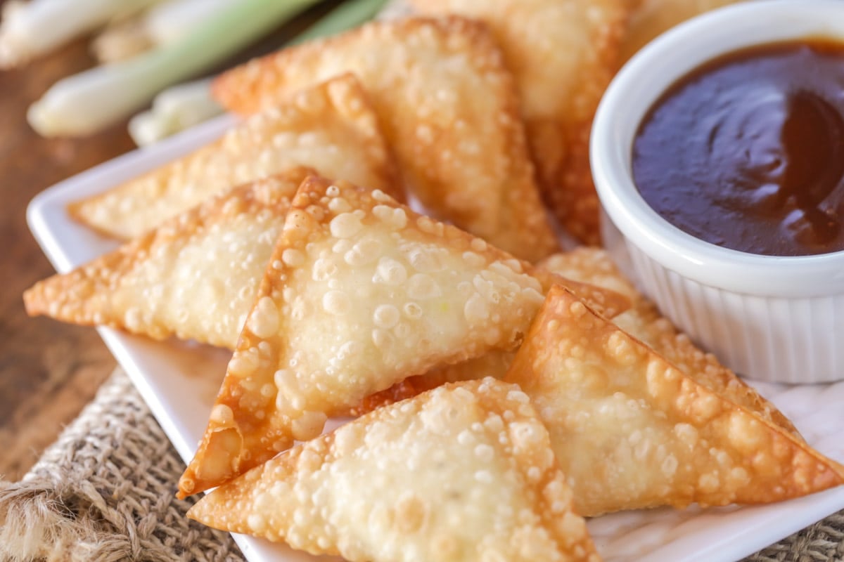 A plate of cream cheese wontons served with dipping sauce.