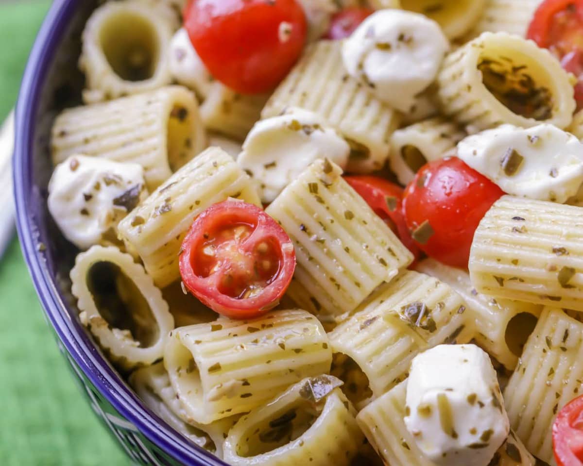 Pesto Pasta Salad topped with tomato halves and mozzarella balls