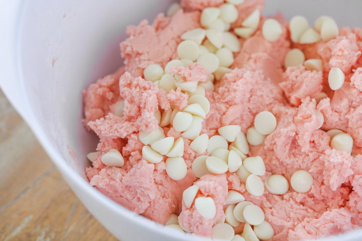 Mixing white chocolate chips into strawberry cookie dough.