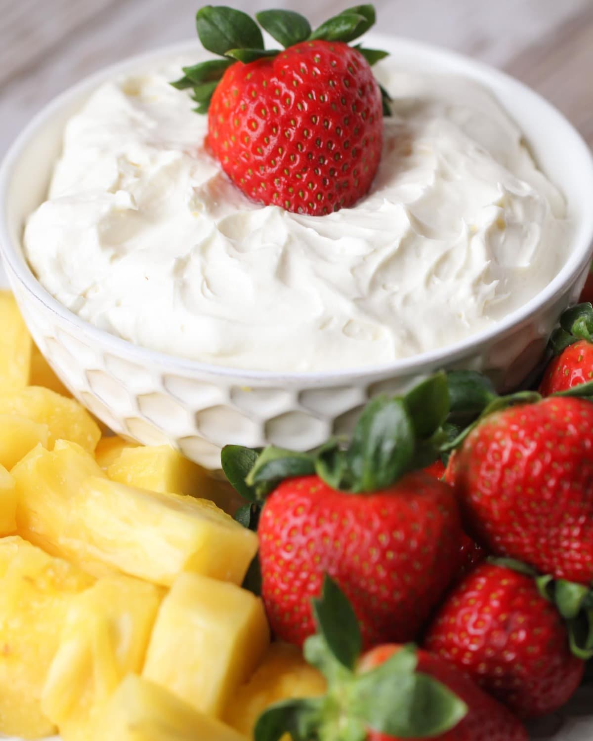 Vanilla yogurt fruit dip in a serving bowl served with fruit on the side.