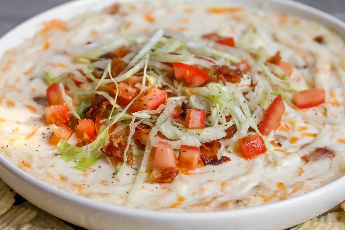Appetizer Dips - BLT dip in a white serving dish topped with bacon crumbles, diced tomatoes and shredded lettuce. 