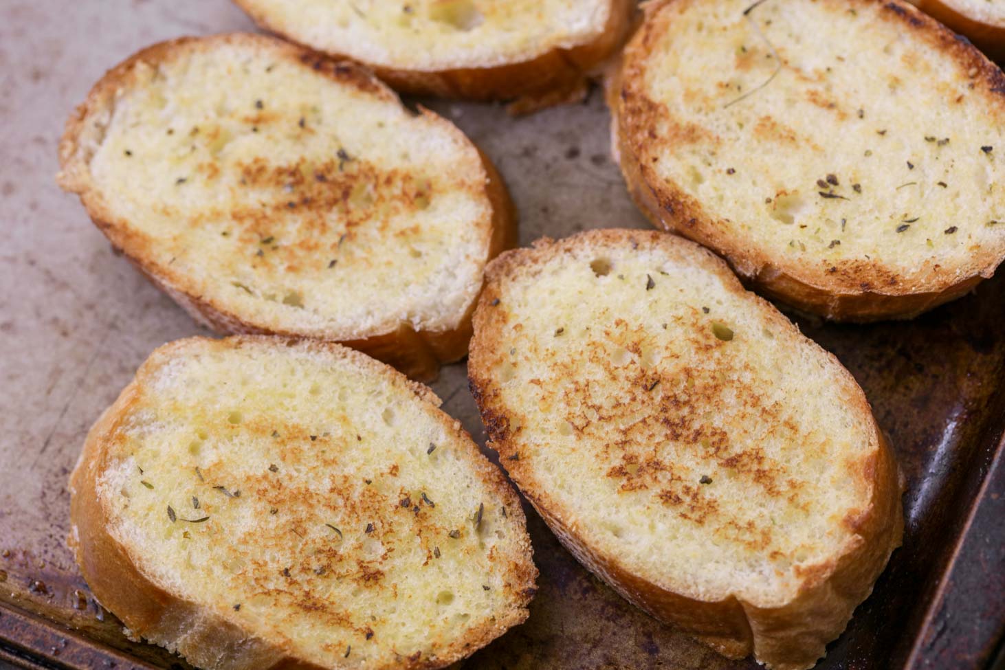 Toasted baguette slices on a baking sheet.