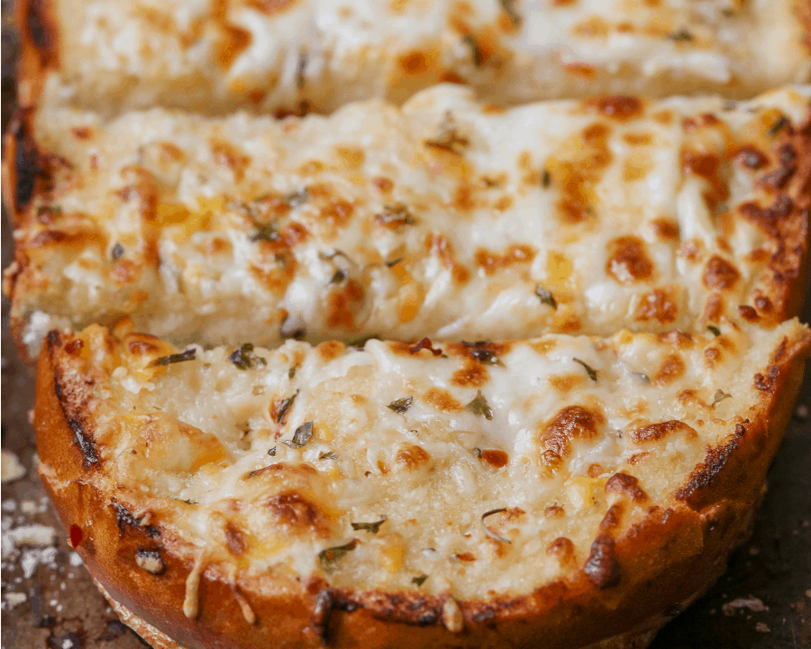 Close up of cheesy garlic bread sliced on a baking sheet.