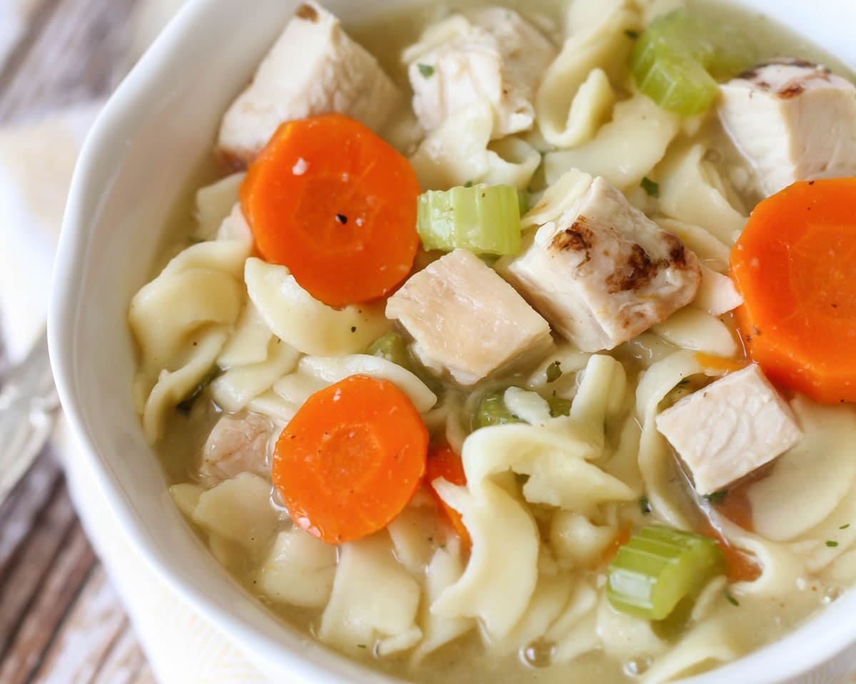 Chicken soup recipes - homemade chicken noodle soup in a white bowl.