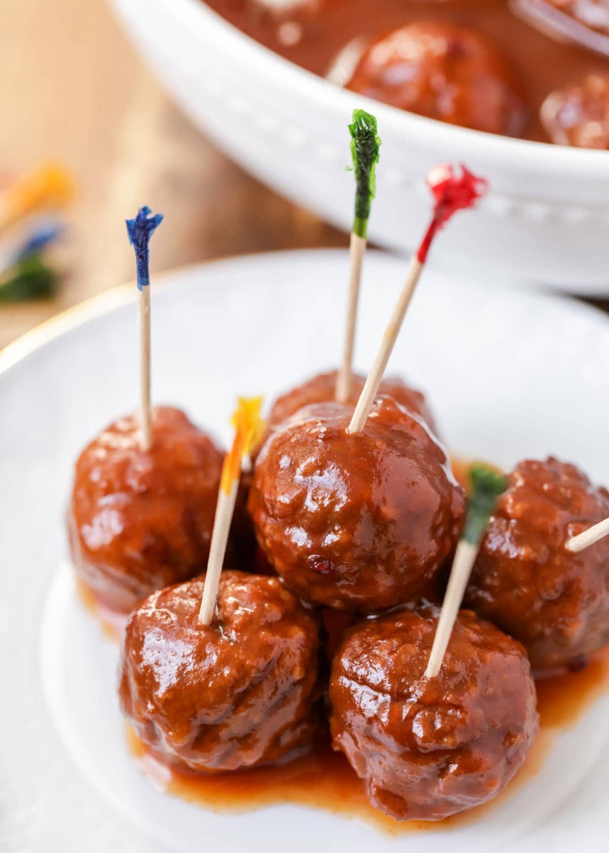 Crock Pot Meatballs stuck with toothpicks and piled on a white bowl.