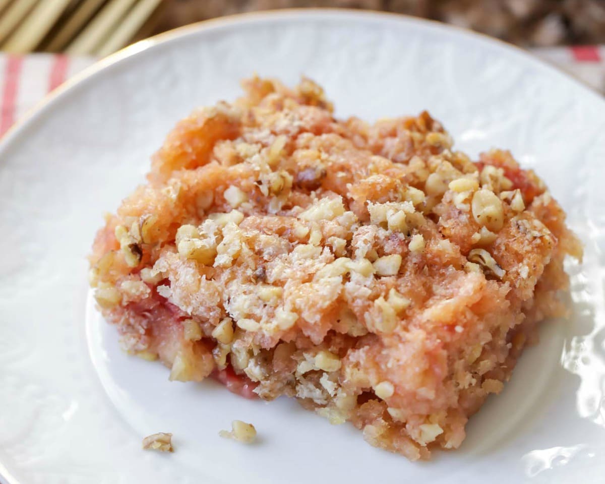 A slice of cherry Dump Cake on a white plate.