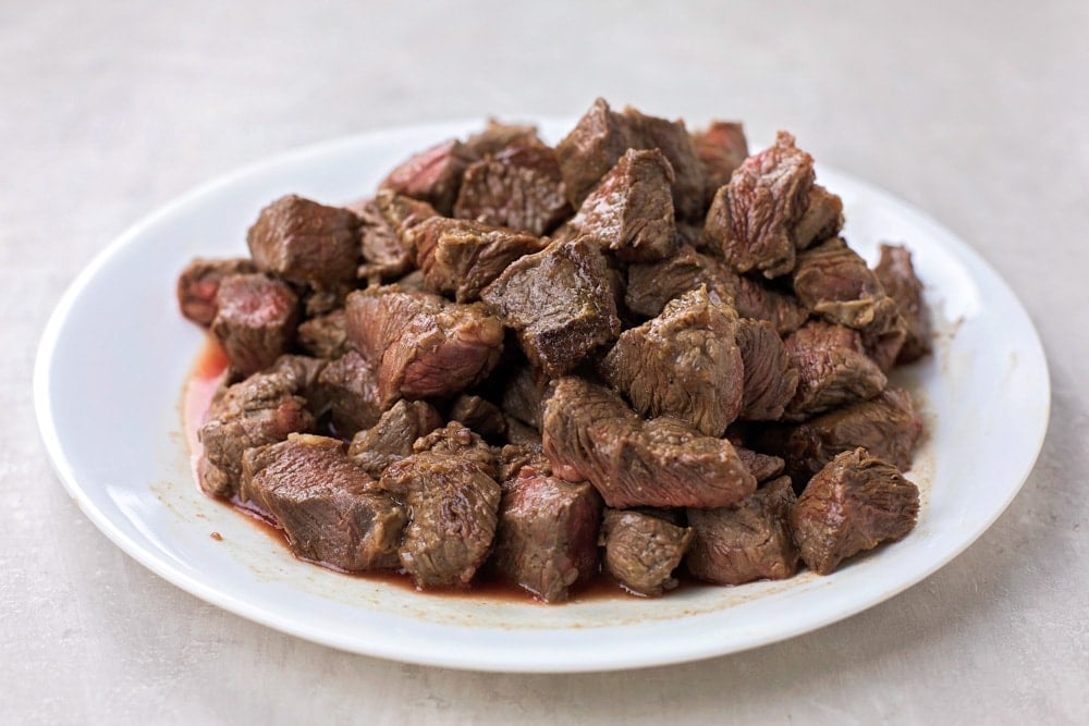 A plate of cooked cubes of beef.