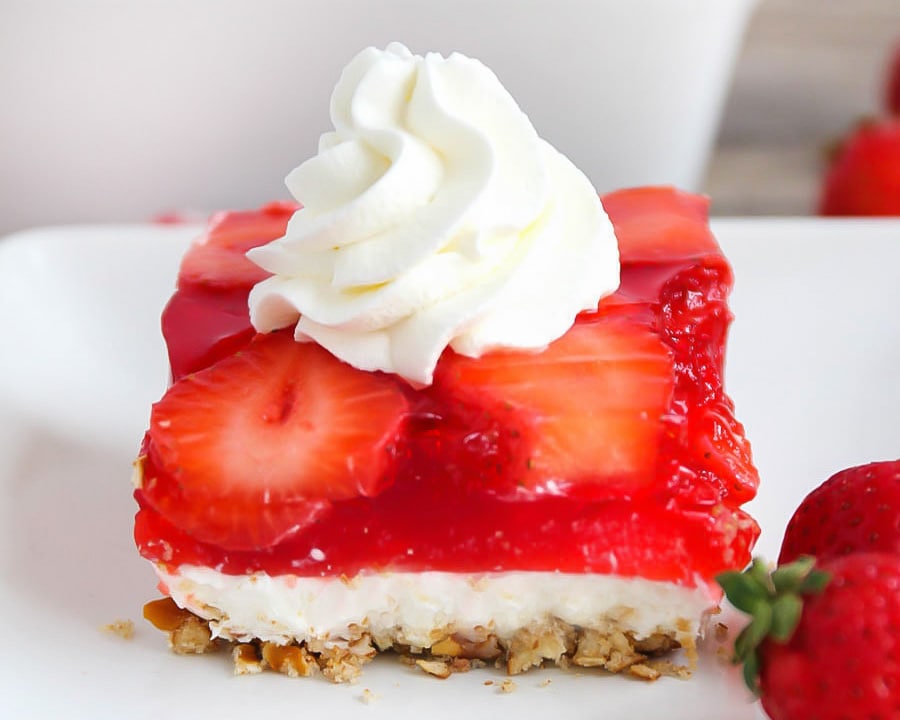 Christmas side dishes - a square slice of strawberry jello pretzel salad topped with whipped cream.