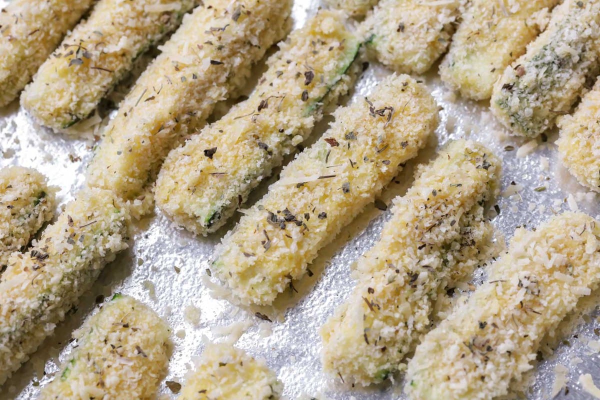 Zucchini Sticks in bread crumbs on baking sheet