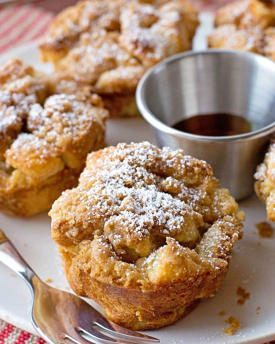 French Toast muffins topped with powdered sugar and served on a plate with syrup.