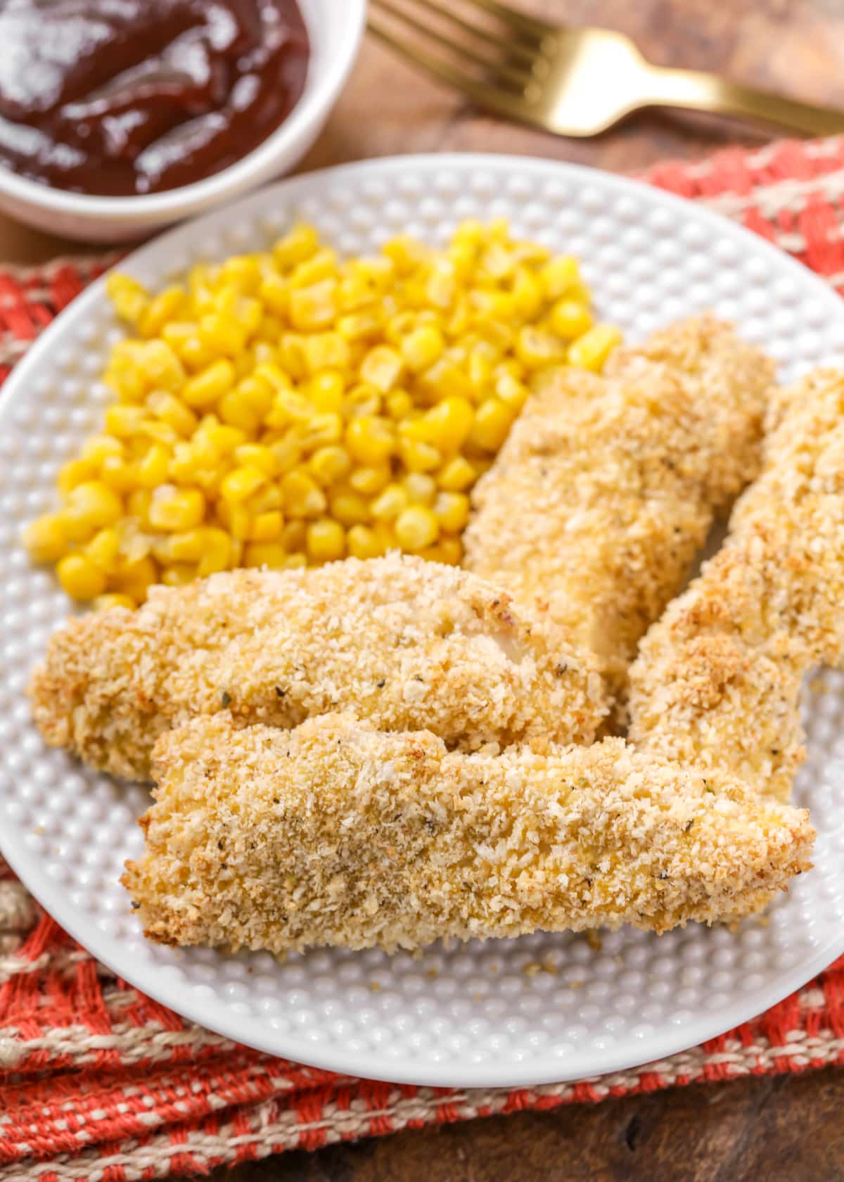 Baked Chicken Tenders Recipe on plate with corn and bbq sauce