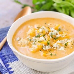 A bowl of buffalo chicken soup topped with bleu cheese and herbs.